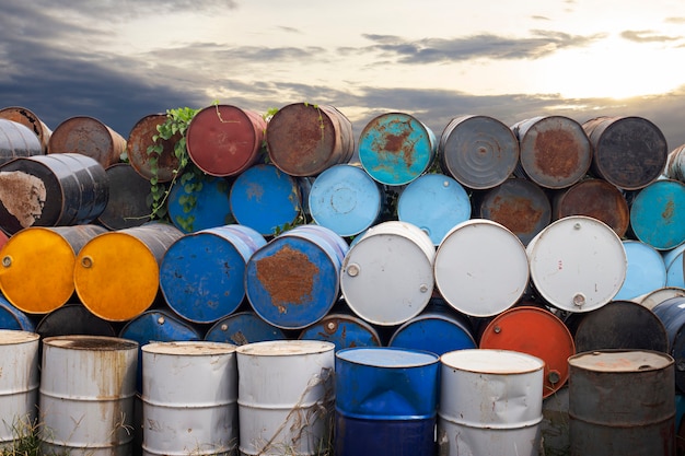 Old metal chemical tanks at sunset sky, dirty oil steel drums,\
environment, chemical disposal