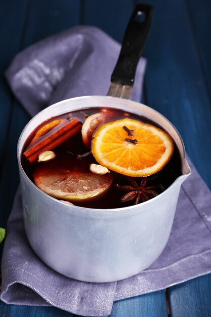 Old metal pan of tasty mulled wine on wooden table