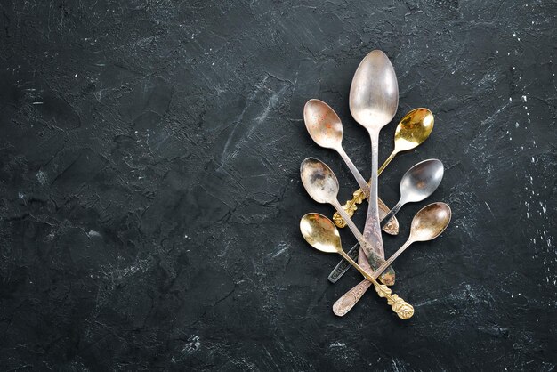 Old metal spoons on a stone background Top view Free space for your text