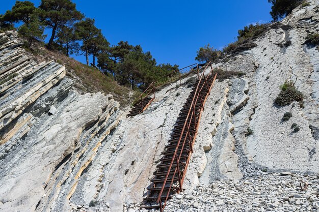 An old metal staircase and massive white rocks on a wild beach.