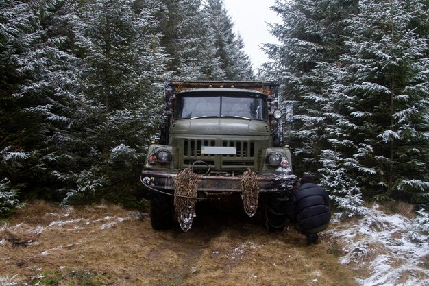 An old military truck in a green swamp with metal chains in the forest Carpathians