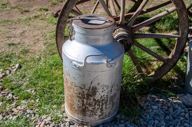 Old milk jar next to horse cart