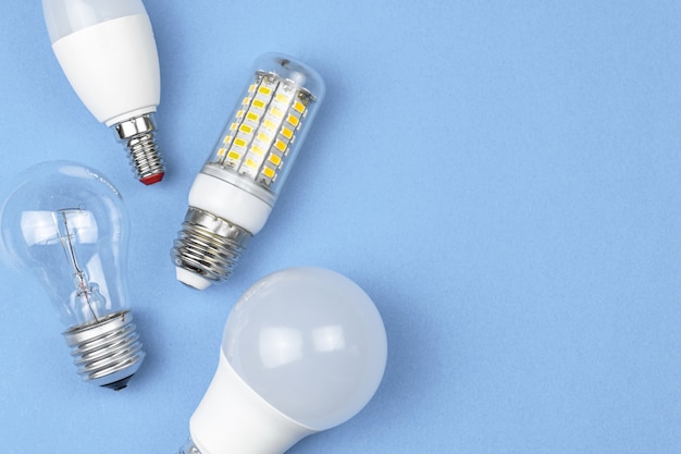 Old and new bulbs together, pastel blue background. Energy saving concept. Flat lay, top view photo