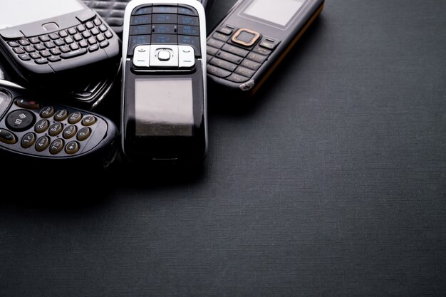 Old and obsoleted cellphones on a black background.