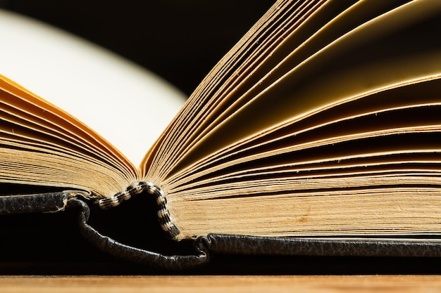 An old open book on a wooden table in a close up view