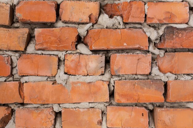 오래 된 주황색 벽돌 벽, 고르지 못한 벽돌입니다.