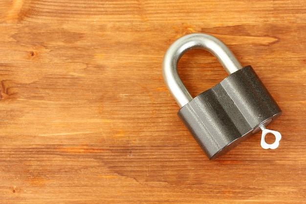 old padlock with key on wooden background closeup