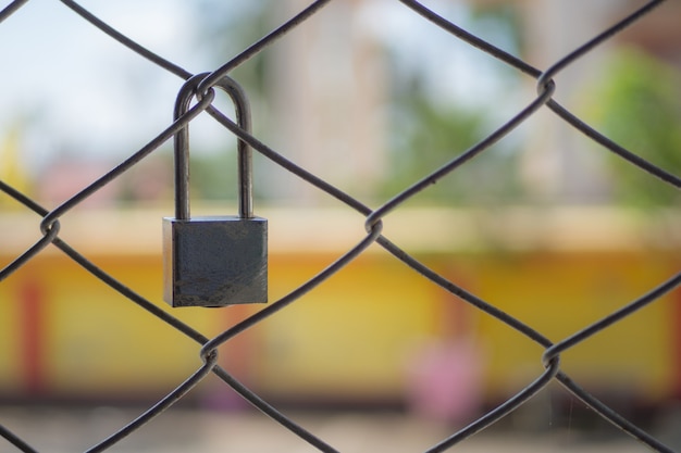 Photo old padlock with metal mesh fence with green bokeh background