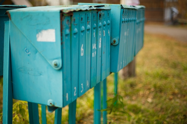 Old painted vertical metal mailboxes outside on sunny day