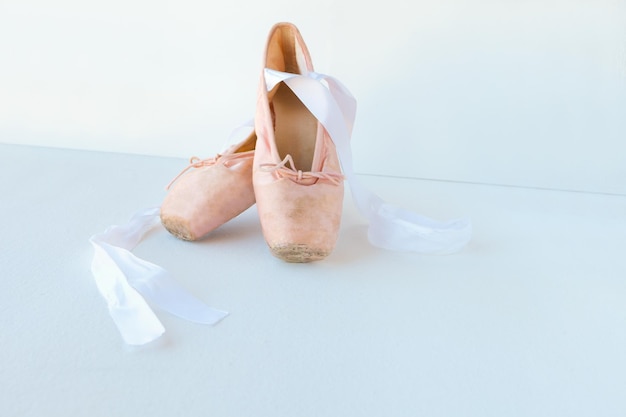 Old pair of neatly arranged ballet shoes on white background with copyspace pointe shoes