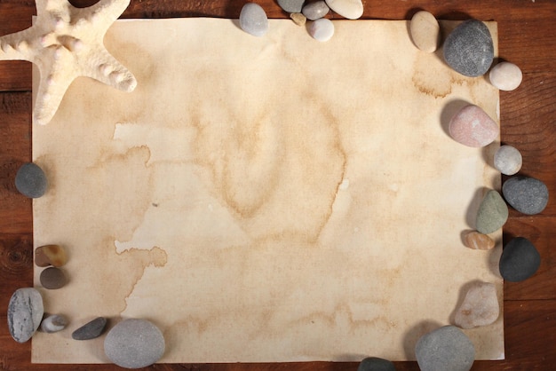 Old paper starfish and stones on wooden table