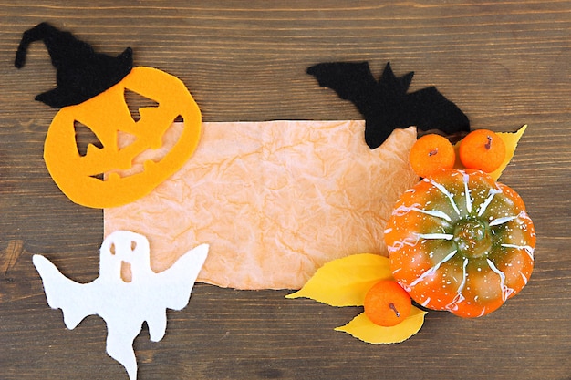 Old paper with Halloween decorations on grey wooden background