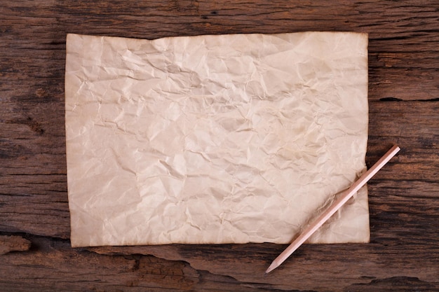 Old paper with pencil on wooden table