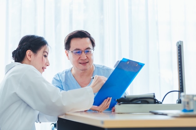 Uomini anziani anziani che parlano con le donne di medico nell'ufficio della clinica