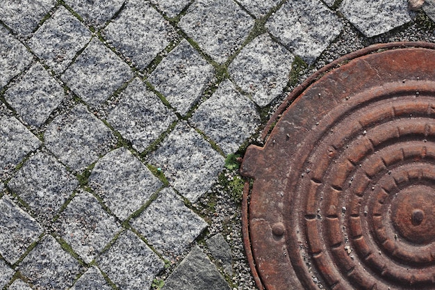 Vecchio blocco di pavimentazione e tombino