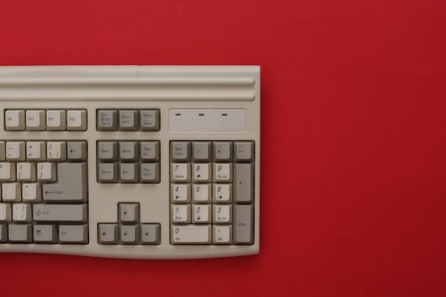 Old pc keyboard on red background. Top view. Flat lay