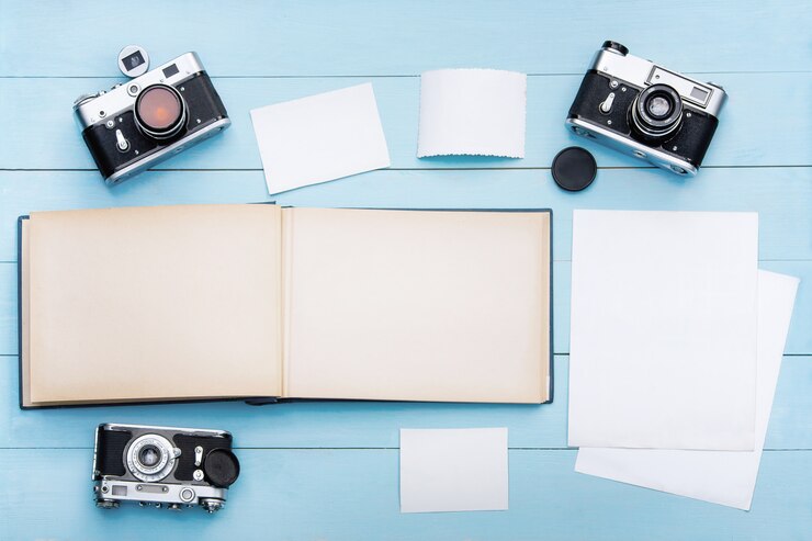 Old photo album with photos on a beautiful wooden table and old cameras.Mockup free.