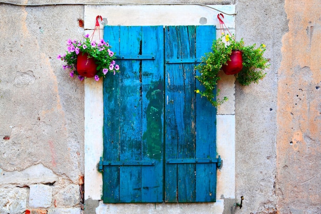Old picturesque window with shutters and flowerpots