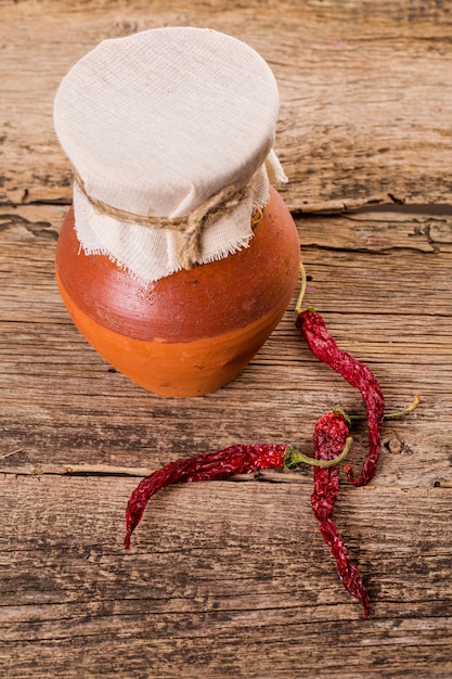 Old pitcher and red dry pepper on wooden table