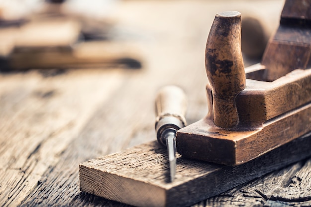 Old planer and other vintage carpenter tools in a carpentry workshop.