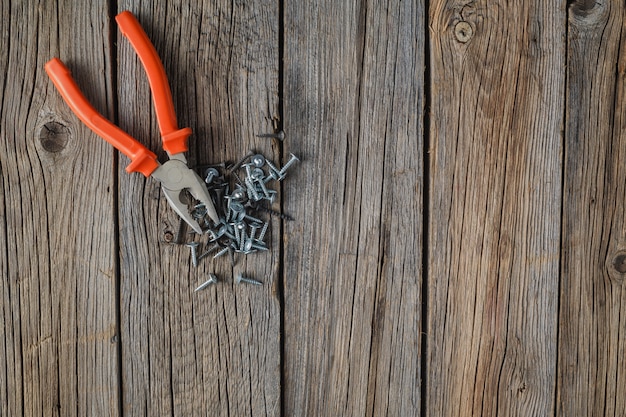 Old pliers on brown wooden background in rustic style.