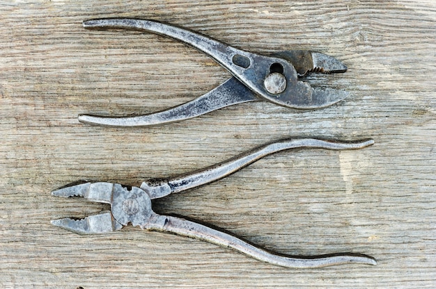 Old pliers on a wooden background.