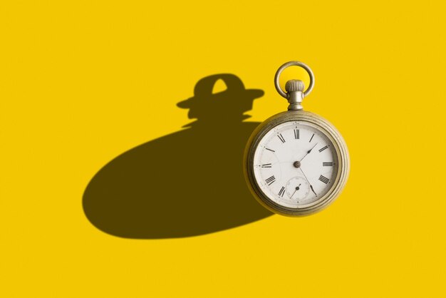 Old pocket clock with a bold shadow in a yellow background