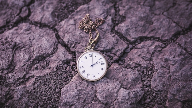 Old pocket watch on dry ground