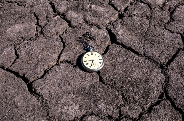 写真 乾いた地面に古い懐中時計