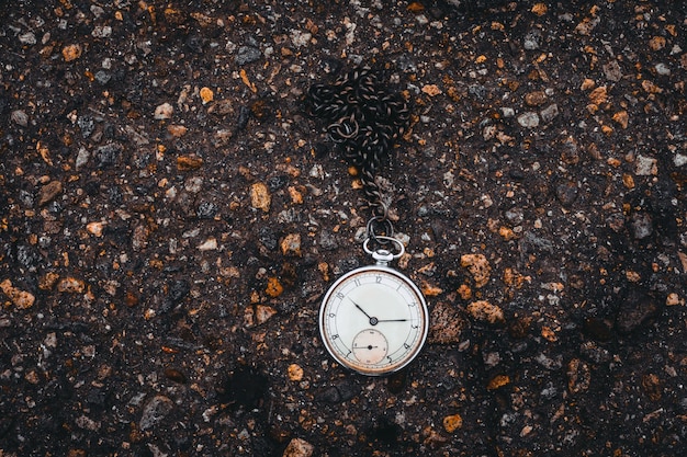 Old pocket watch on the road. Time concept.