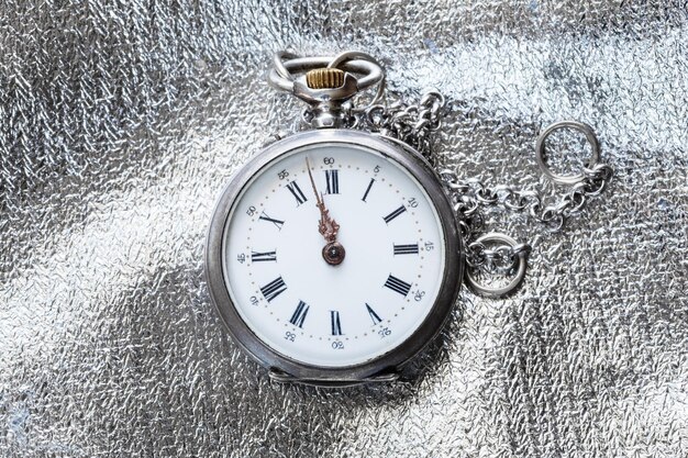 Old pocket watch on silver fabric background