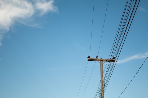 an old Power pole with line on blue sky background,  lots of copy space at left