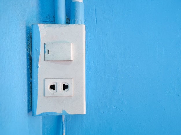 Old power sockets and switches are mounted on blue cement walls
inside the building.