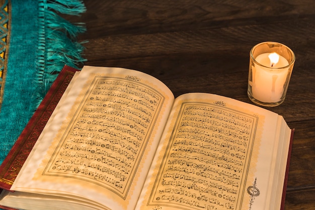 Photo old quran lying near candle