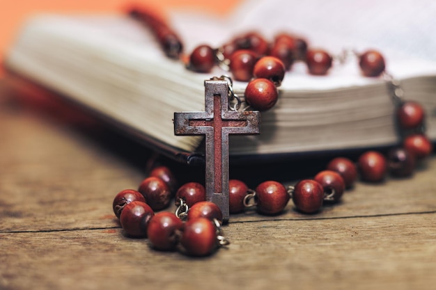 Photo old red beads and crucifix on a bible beautiful coral orange background religion concept