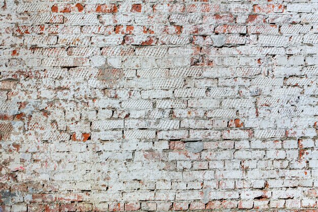 Old red brick wall with peeling plaster