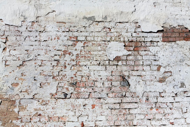 Old red brick wall with peeling plaster