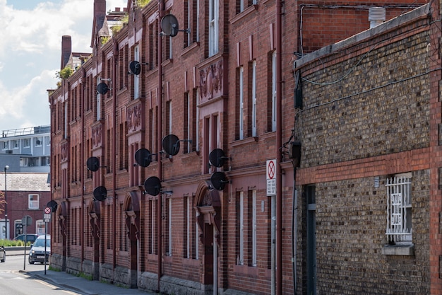 Old red bricks building with many satelite dishes on the wals.