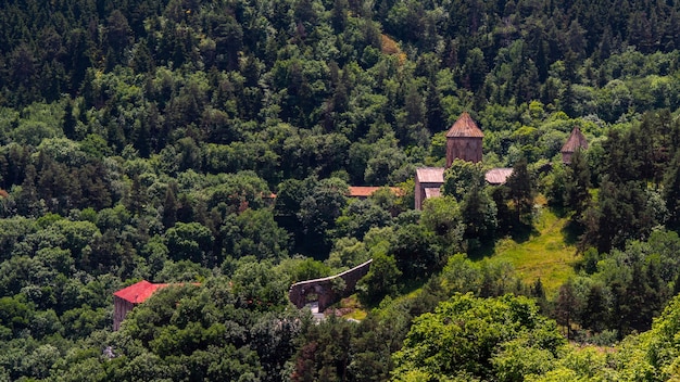 Old red church lost in the mountain forest. Ancient Georgian christian monastery