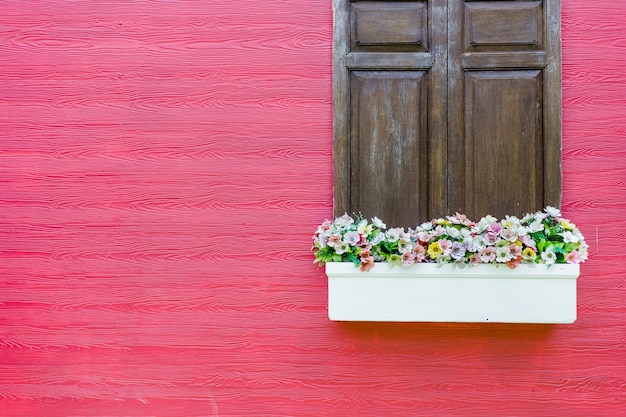 Old red house with wooden window and flowers