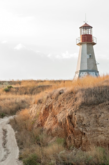 Foto vecchio faro rosso su una collina di paglia secca