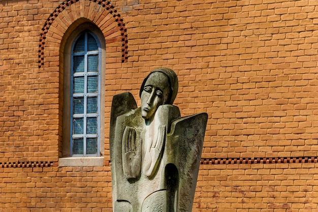 An old religious statue of crying woman on the background of the brick facade of building o