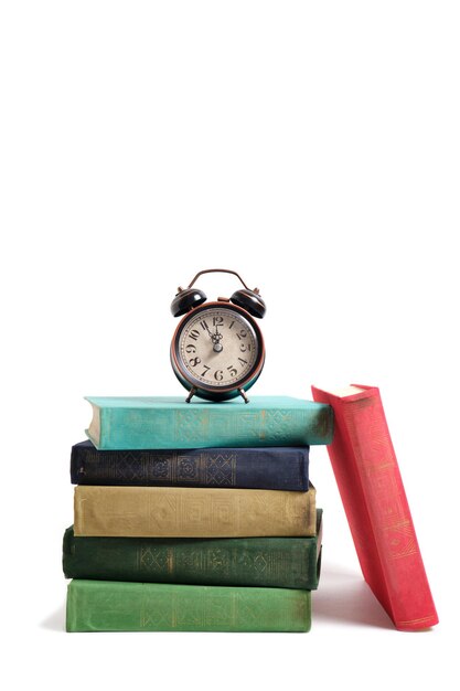 Old, retro alarm clock on a stack of vintage books on a white background.
