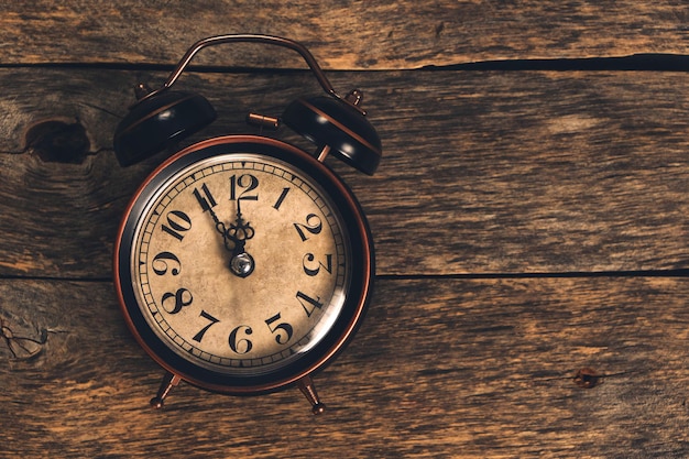 Old retro alarm clock on wooden table. Time is ticking and the hands.