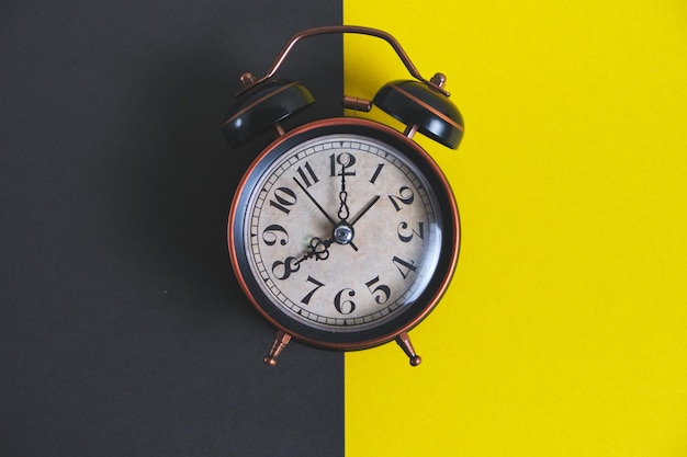 Old retro alarm clock on a yellow and black background.