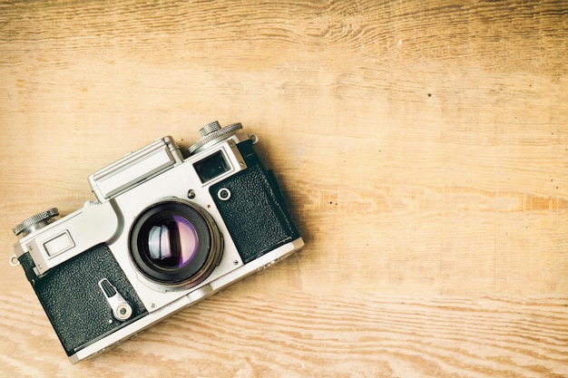 Old retro camera on vintage rustic wooden planks boards. Education photography courses back to school concept abstract background. Close up, top view, copy space.