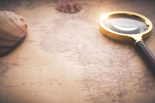 シェルと虫眼鏡で世界の古いレトロな地図が押されています。休暇、レクリエーション、旅行。明るい日光。