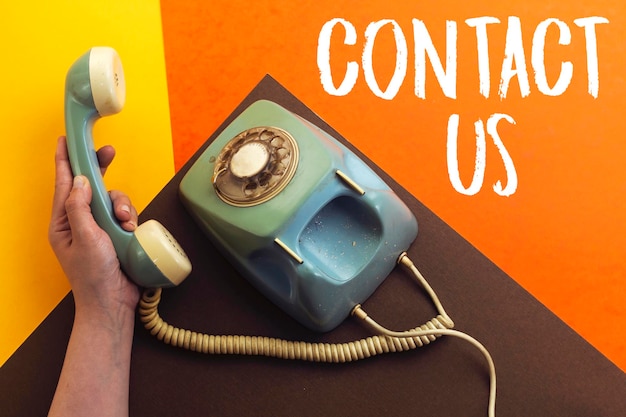 old retro phone and hand holding handset with contact us concept