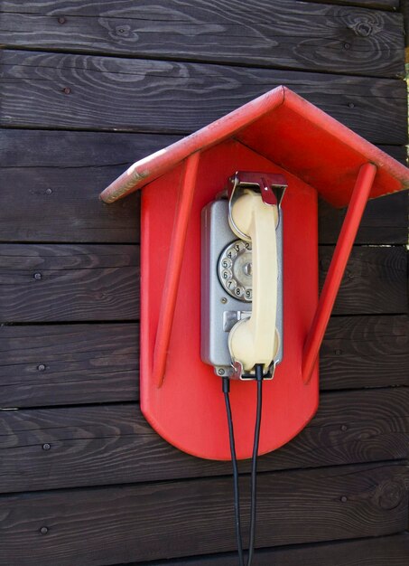 Old retro red wall phone on wood background