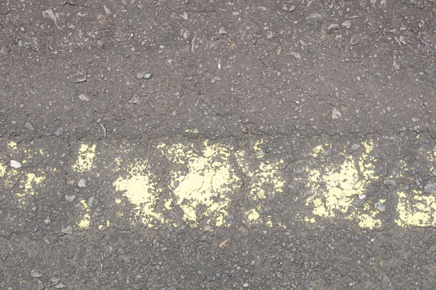 Old road surface has yellow lines peeling off